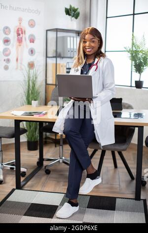 Videocall für TeleheHealth, virtueller Remote-Chat. Afrikanische Ärztin lächelt der Kamera zu, während sie die Patientin online über einen Webcam-Videoanruf auf dem Laptop konsultiert. Stockfoto