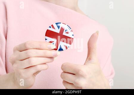 Die Flagge von Großbritannien, allgemein bekannt als Union Jack auf Knopf Abzeichen gedruckt, hält von Frau in ihrer schönen Hand. Stockfoto