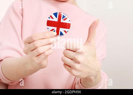 Die Flagge von Großbritannien, allgemein bekannt als Union Jack auf Knopf Abzeichen gedruckt, hält von Frau in ihrer schönen Hand. Stockfoto