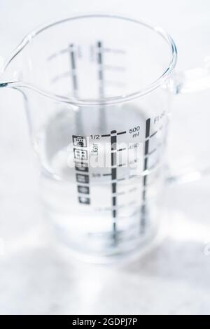 Backpulver und Essig in Glasbehältern zur Reinigung von emailliertem Gusseisen-Braiser. Stockfoto