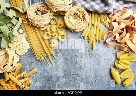 Gemischte Arten und Formen der italienischen Pasta auf grauem Stein, Hintergrund. Speicherplatz kopieren. Stockfoto