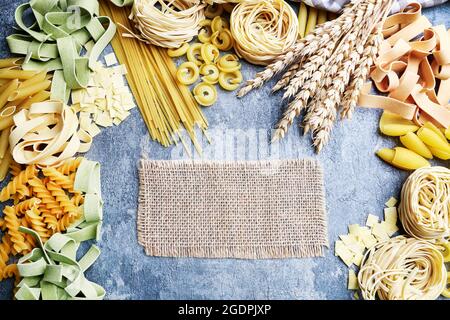 Gemischte Arten und Formen der italienischen Pasta auf grauem Stein, Hintergrund. Speicherplatz kopieren. Stockfoto