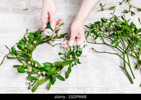 Florist bei der Arbeit: Wie man Misteltürkranz macht, Schritt für Schritt, Tutorial. Stockfoto