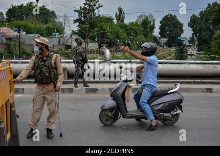 Srinagar, Indien. August 2021. Ein Mann auf dem Roller wird vor dem indischen Unabhängigkeitstag in Srinagar an einem Sicherheitskontrollpunkt angehalten. Da Indien am 15. August 2021 seinen 75. Unabhängigkeitstag feiert, wurde die Sicherheit in Kaschmir verschärft, da die Streitkräfte auf „technische Überwachung“, einschließlich des Einsatzes von Drohnen zur Überwachung der Situation, zurückgriff. Kredit: SOPA Images Limited/Alamy Live Nachrichten Stockfoto