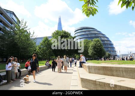 Genießen Sie das Sommerwetter und spazieren Sie auf dem Queen's Walk am Potters Field Park mit Rathaus und The Shard Beyoun, Southwark, London, Großbritannien Stockfoto