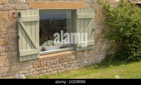 Blick auf ein Fenster von außen mit grünen Fensterläden Stockfoto
