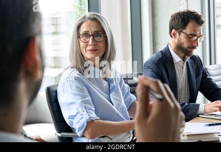 Lächelnde weibliche ceo, die beim Tischgespräch den männlichen Kollegen der Führungskraft anschaut. Stockfoto