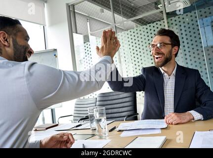 Zwei glückliche, vielfältige Partner, Geschäftsleute, die im Konferenzraum fünf hoch gaben. Stockfoto