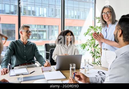 Glückliches, vielfältiges Unternehmensteam, das im Vorstandsbüro über das Projekt spricht. Stockfoto