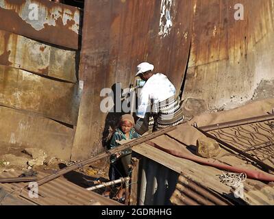 Soweto South Africa, August 15 2007; Frau an der Wasserpumpe mit Kind in einer Kleinstadt, die lebt und Häuser mit einigen Worten hat, die ärmsten Menschen, die um Exis kämpfen Stockfoto