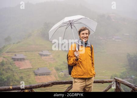 Mann Tourist mit Regenschirm in Sapa im Nebel, Nordwest-Vietnam. Vietnam Reisekonzept. UNESCO-Weltkulturerbe. Vietnam öffnet sich nach Quarantäne für den Tourismus Stockfoto