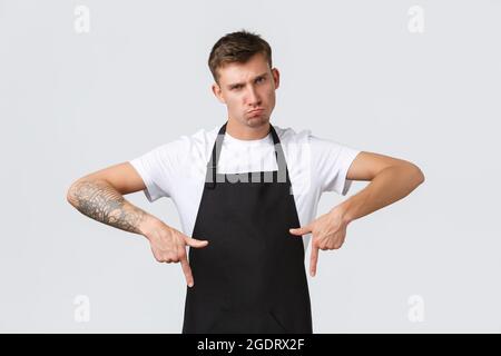 Inhaber kleiner Unternehmen, Café und Konzept des Personals. Düster und skeptisch Barista in schwarzer Schürze Pouting, wird immer traurig, wenn der Kunde nicht klicken Stockfoto