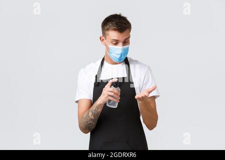 Coronavirus, soziale Distanzierung in Cafés und Restaurants, Geschäft während Pandemie-Konzept. Barista, Mitarbeiter des Coffee House, der die Hände mit der Hand desinfiziert Stockfoto