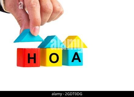 Die Hand des Geschäftsleuten platziert einen Holzhausblock mit einem isolierten HOA-Wort auf Weiß Stockfoto