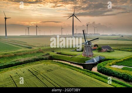Niederlande. Eemshaven. Windpark Eemsmond. Windenergieanlagen. Hintergrund: Alte Windmühle (1897) namens Goliath. Sonnenaufgang. Antenne. Stockfoto