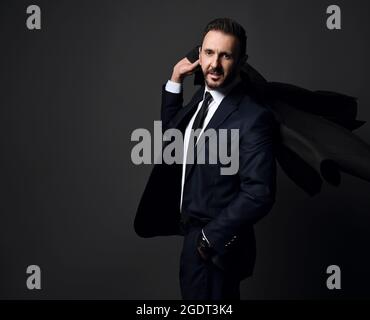 Eleganter bärtiger Geschäftsmann, Chef im stilvollen, modernen Büroanzug, der seinen Mantel auf der Schulter hält Stockfoto