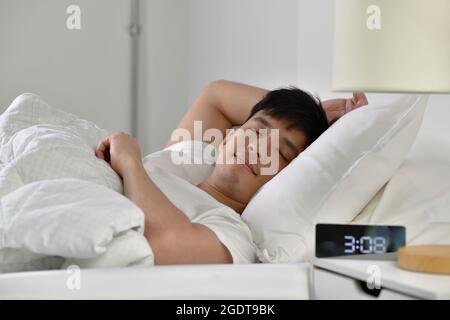 Schöner junger asiatischer Mann schläft im Bett Stockfoto