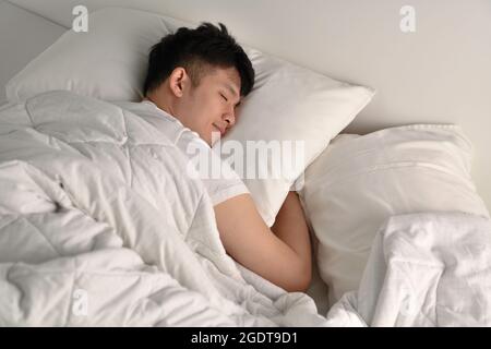 Schöner junger asiatischer Mann schläft im Bett Stockfoto