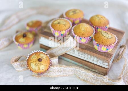 Frische, hausgemachte Bananenmuffins, dekoriert mit Schokoladenchips und Bananen in Scheiben auf dem Tisch Stockfoto