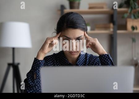 Nachdenkliche Inderin betrachtet Laptop-Denken Stockfoto
