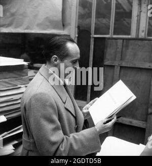 Regisseur RENE CLAIR am Set Candid hält sein Szenario während der Dreharbeiten von LE SILENCE EST D'OR / MAN ABOUT TOWN 1947 Regisseur / Szenario und Dialog RENE CLAIR Koproduktion Pathe Consortium Cinema / RKO Radio Picches Stockfoto