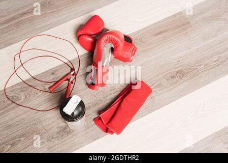 Draufsicht auf Boxhandschuhe, Seil, Flasche und ein rotes Handtuch auf einem Holzhintergrund Stockfoto