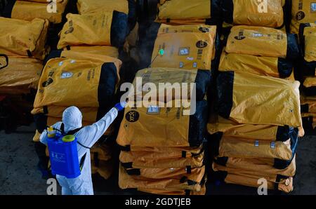 Haikou, Chinas Provinz Hainan. August 2021. Ein Mitarbeiter desinfiziert ein Lagerhaus in einem Lieferverkehrszentrum in Haikou, südchinesische Provinz Hainan, 15. August 2021. Quelle: Yang Guanyu/Xinhua/Alamy Live News Stockfoto