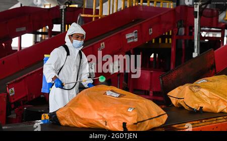 Haikou, Chinas Provinz Hainan. August 2021. Ein Mitarbeiter desinfiziert E-Mails in einem Transportzentrum in Haikou, südchinesische Provinz Hainan, 15. August 2021. Quelle: Yang Guanyu/Xinhua/Alamy Live News Stockfoto