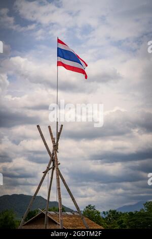 Eine vertikale Aufnahme der wehenden thailändischen Flagge auf der Stange gegen einen bewölkten Himmel Stockfoto