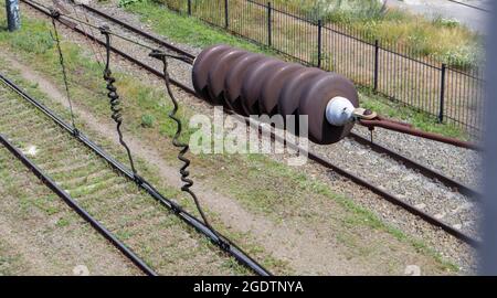 Eine oberirdische Stromleitungskomponente der Eisenbahn entlang einer Strecke mit einem Elektrifizierungssystem der Schiene, das einen elektrischen Zug mit Strom versorgt. Oberleitungskabel Stockfoto