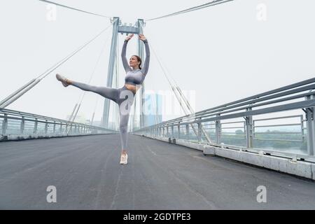 Frau gekleidet Leggings und Top mit Tanz in der Stadt Backgroud. Gesundes Sport-Lifestyle-Konzept. Aktive und sportliche weibliche Übungen Stockfoto