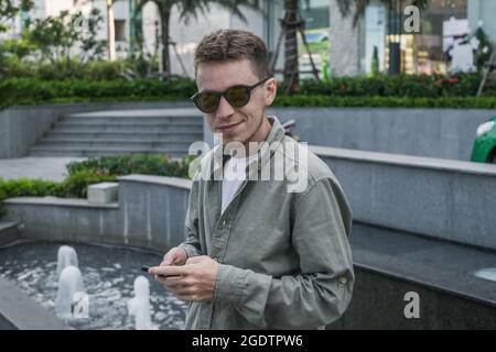 Porträt eines jungen kaukasischen Mannes mit Sonnenbrille in hellgrünem T-Shirt und lächelnd. Hochwertige Fotos Stockfoto