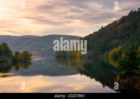 Schöne Abendlandschaft mit See. Glühende Wolken spiegeln sich auf der Wasseroberfläche. Wunderbare herbstliche Landschaft in den Bergen rumäniens Stockfoto