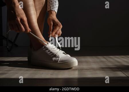 Frau zog neue weiße Leder-Sneakers an Stockfoto