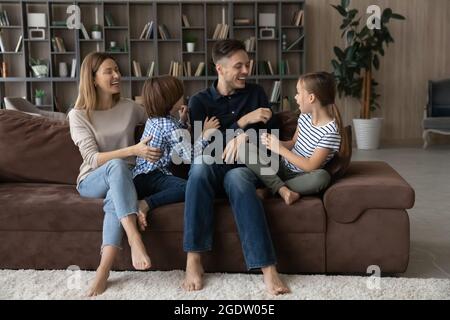 Glückliches Paar und Kinder kitzeln sich gegenseitig und haben Spaß in der Halle Stockfoto