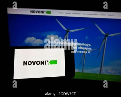 Person, die das Smartphone mit dem Logo des australischen Batterieunternehmens Novonix Limited auf dem Bildschirm vor der Website hält. Konzentrieren Sie sich auf die Telefonanzeige. Stockfoto