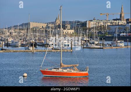 Wunderschöne Nahaufnahme am Abend Blick auf das rote Boot und die Yachten, die am West Pier des Hafens von Dun Laoghaire, Dublin, Irland, festgemacht sind. Weicher und selektiver Fokus Stockfoto