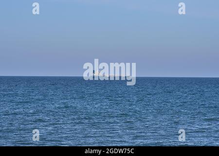 Wunderschöne Abendansicht des Frachtschiffes in der Irischen See vom West Pier des Hafens von Dun Laoghaire, Dublin, Irland. Selektiver Fokus. Minimalismus Stockfoto