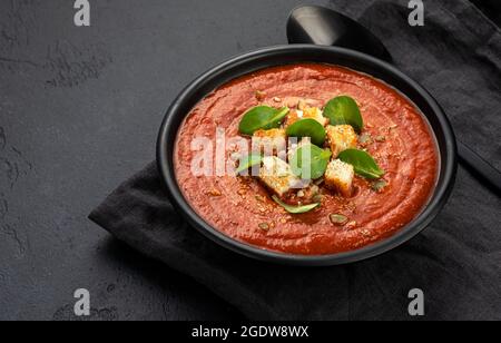 Schüssel Tomatensuppe auf schwarzem Hintergrund Stockfoto
