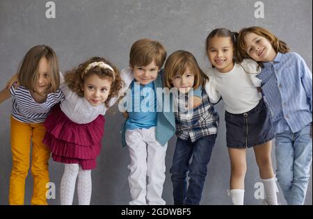 Gruppenportrait von glücklichen kleinen Kindern, die im Studio stehen, sich duscheln und lächeln Stockfoto