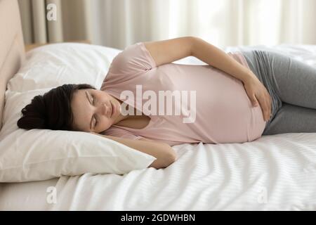 Ruhige junge, schwanger Frau, die sich im Bett ausruhte und friedlich schlief Stockfoto