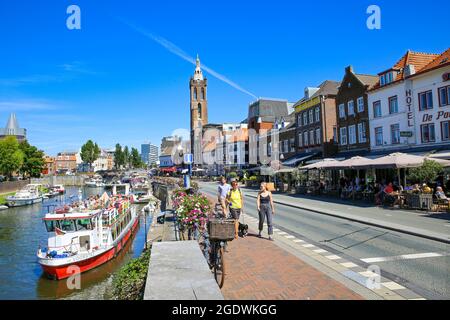 Roermond, Niederlande - Juli 9. 2021: Blick auf die Fußgängerzone mit Straßencafés und Restaurants am Wasserkanal mit Booten, Stadtbild und alter Kirche Stockfoto
