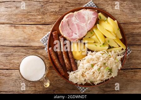 Wurst, Kassler-Schweinehals, gekochte Kartoffeln, Sauerkraut und Senf ist ein traditionelles deutsches Wintergericht aus der Nähe auf dem Tisch. Horizontale Ansicht von oben Stockfoto