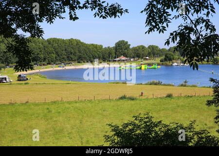 Roermond (Noorderplas), Niederlande - Juli 9. 2021: Blick auf idyllischen Badesee mit Wald und Sandstrand gegen blauen Sommerhimmel Stockfoto