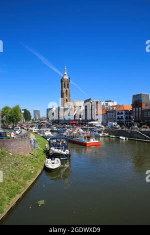 Roermond, Niederlande - Juli 9. 2021: Blick auf den geschäftigen holländischen Wasserkanal mit Stadtbild und altem Kirchturm vor blauem Sommerhimmel Stockfoto