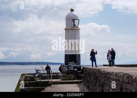 Familie, die am Ende eines Piers fotografiert hat, wo Männer davon fischen. Stockfoto