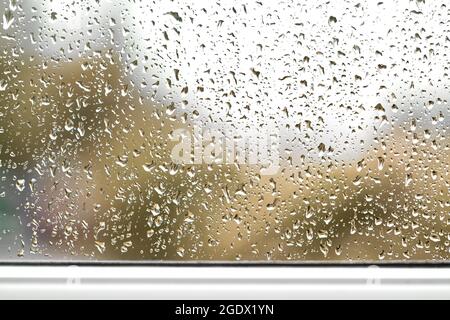 Regentropfen auf der Fensterbrille, verschwommener Blick auf den Herbst, schlechtes Wetter Stockfoto