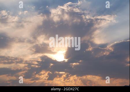 Die letzten Sonnenstrahlen bei Sonnenuntergang beleuchten einen Wolkenhaufen. Wolken brechen durch und erzeugen raue Formen, umgeben von einem wolkigen Sturmhimmel aro Stockfoto