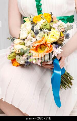 Frau in weißem Kleid mit einem Hochzeitsstrauß aus Mohnblumen und Nelken. Partyzeit Stockfoto