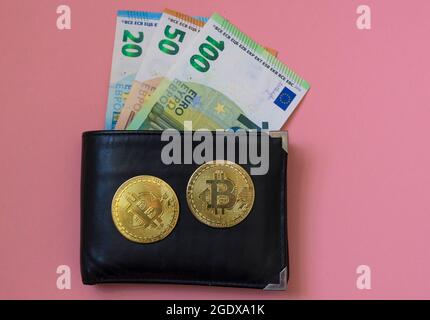 Schwarze Leder-Geldbörse mit Euro-Währung und Bitcoin BTC Krypto-Goldmünzen, neues virtuelles Geldkonzept. Mining- oder Blockchain-Technologie Stockfoto